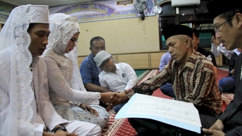 Maskur (pakai batik), menyalami putrinya, usai mempelai pria mengucapkan ijab kabul, di Masjid Baitur Rahmat, Mapolres Metro Jakarta Barat, Jumat (14/12/2018).