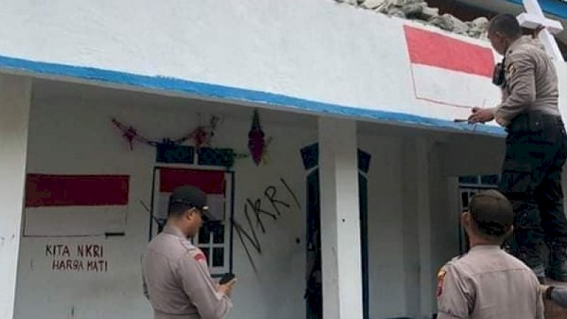 Polisi menggambar bendera merah putih di kantor bekas KNPB Timika, Papua Barat.