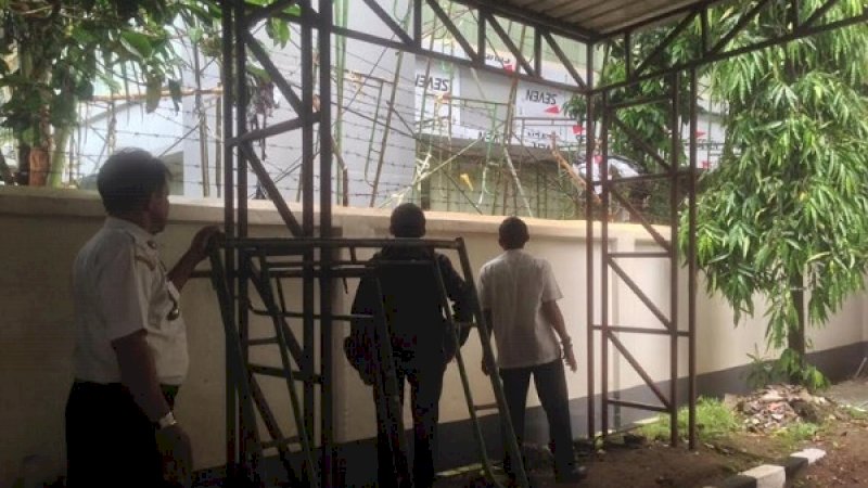 Tiga orang melihat scaffolding tower DPRD Sulsel yang rubuh dan menimpa gedung Pengadilan Tinggi Makassar, Rabu (2/1/2019).