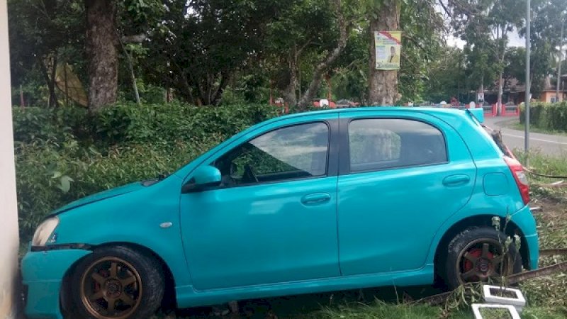 Mobil biru tosca menerobos pagar, lalu menabrak rumah.