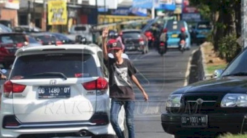 Aksi Pak Ogah di salah satu ruas jalan Kota Makassar.