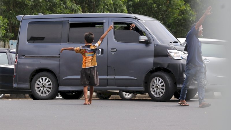 Pengendara mobil memberikan uang kepada Pak Ogah di persimpangan Jalan Urip Sumoharjo , Makassar, Rabu (9/1/2019). Foto/Arfa Ramlan