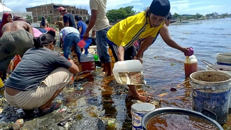 Warga Parepare, menimba tumpahan solar di laut Soreang, Kamis (10/1/2019).