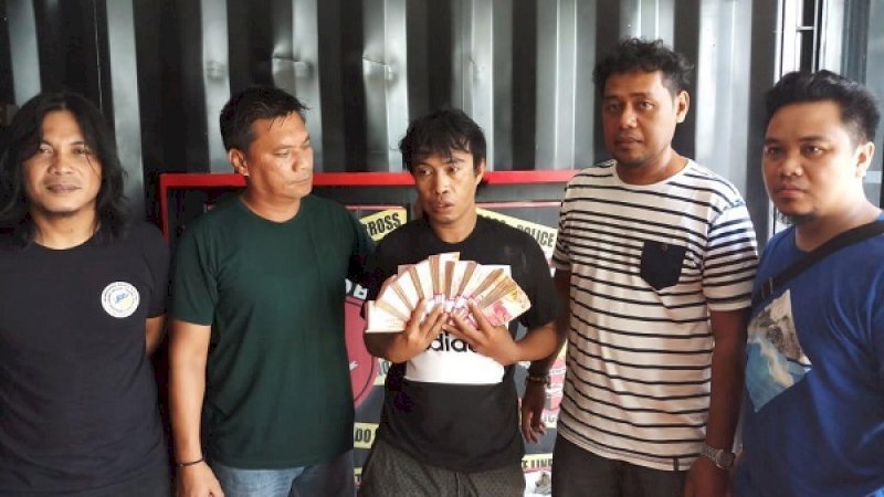 Pelaku Thamrin alias Tabo (38) memegang uang hasil curian saat diamankan polisi.