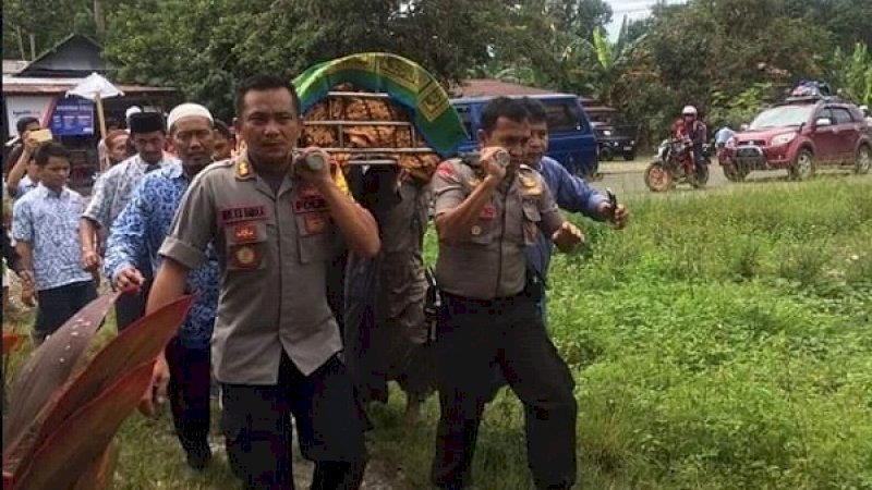 Kapolres Lutra, AKBP  Boy FS Samola (kiri) dan Kapolsek Baebunta, Iptu Budi Amin, ikut mengangkat jenazah Ustaz Maulana Hasan ke peristirahatan terakhir.