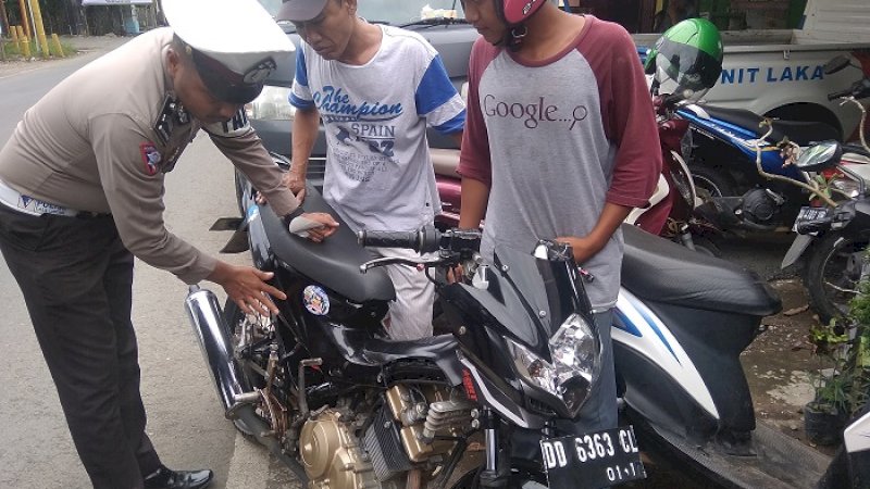 Polisi menempelkan stiker pada motor salah seorang warga Takalar, Sabtu (19/1/2019).