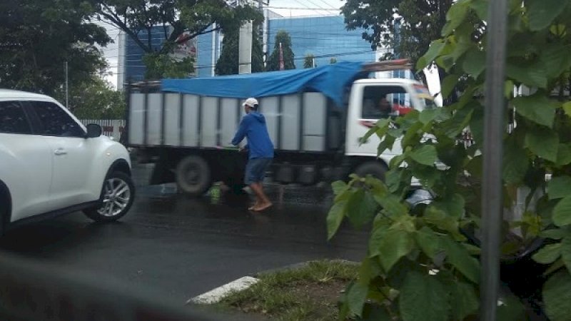 Seorang Pak Ogah, tampak sedang memandu kendaraan berbelok di jalan raya, Jl Urip Sumoharjo, Makassar, Senin (21/1/2019).