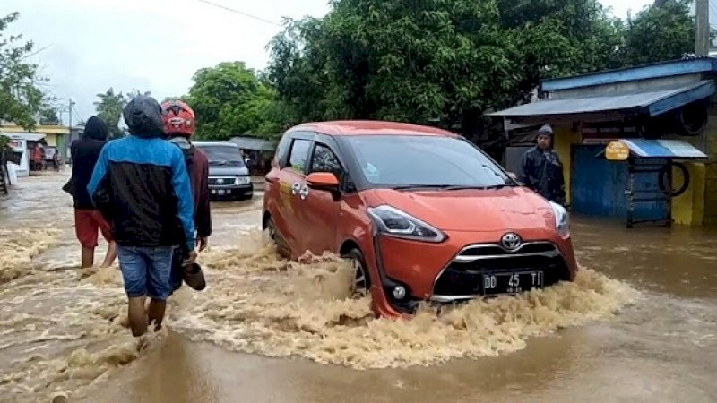 Sebuah kendaraan nekat menerobos banjir di Sarroangin, Jeneponto, Rabu (23/1/2019).