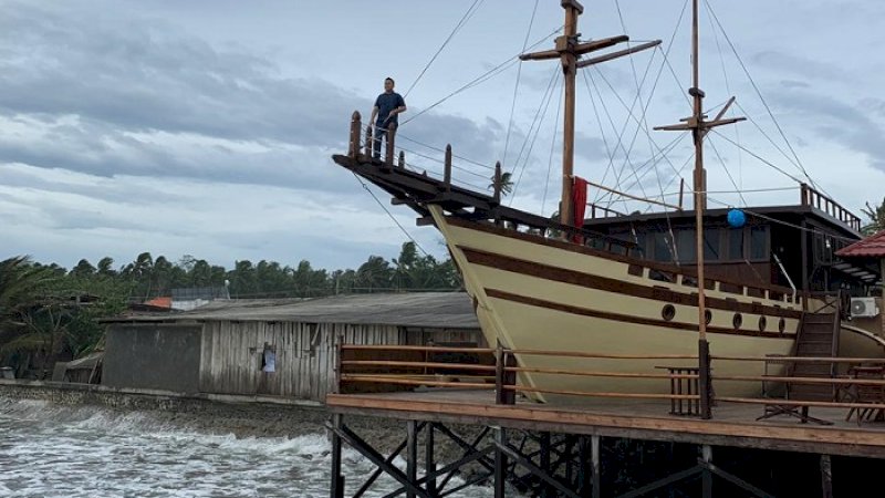 Yasir Machmud memantau dampak cuaca ekstrem di atas miniatur perahu Pinisi di Bulukumba.