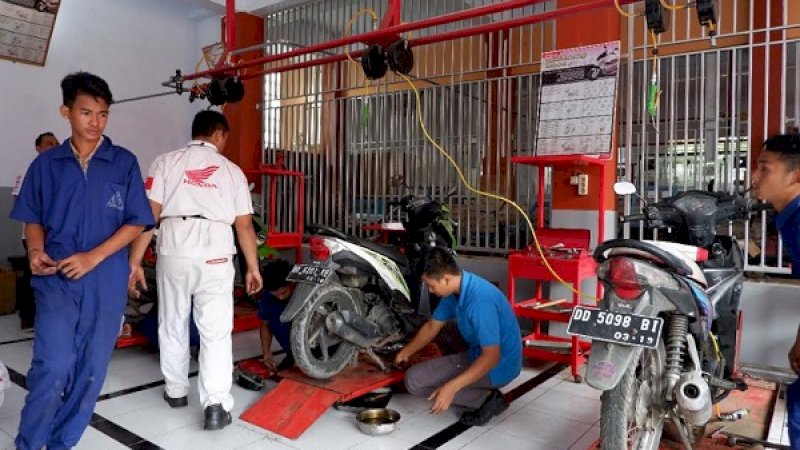 Siswa SMK dengan diawasi teknisi Honda, memperbaiki sepeda motor korban banjir dengan cuma-cuma.