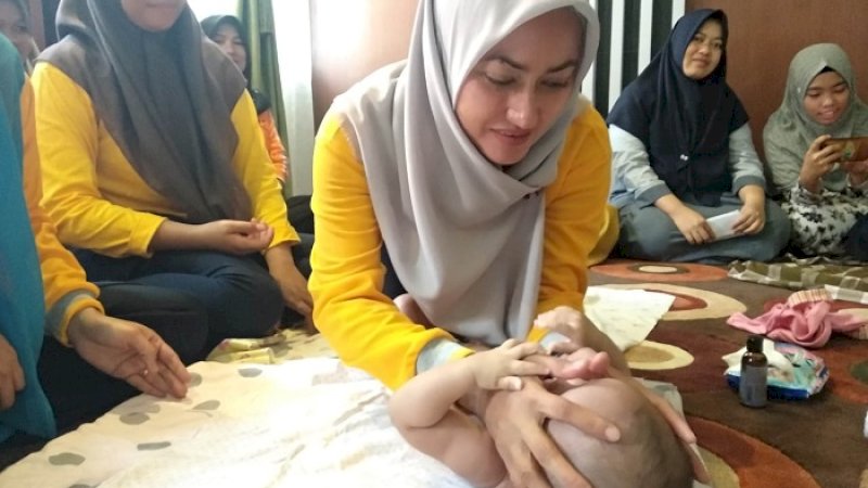 Bupati Luwu Utara Indah Putri Indriani memijat seorang bayi pada launching Komunitas Kelas Terindah, Jumat (1/2/2019). (FOTO-DOK HUMAS PEMKAB LUWU UTARA)