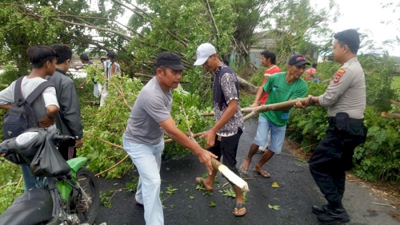  Bhabinkamtibmas Desa Layoa, Bripka Muh Asdar turun langsung menyingkirkan pohon tumbang di wilayahnya.