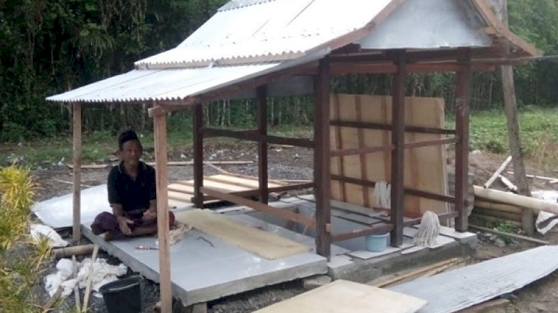 Katte Sukkiri, tampak duduk di samping liang lahatnya di TPU Dusun Sekkang, Desa Massulowalie, Kecamatan Mattiro Sompe, Kabupaten Pinrang.