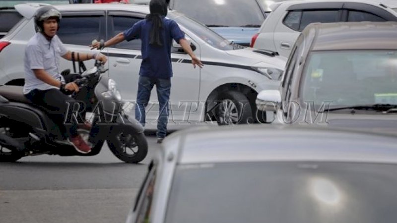 Aksi Pak Ogah di salah satu sudut jalan Kota Makassar.