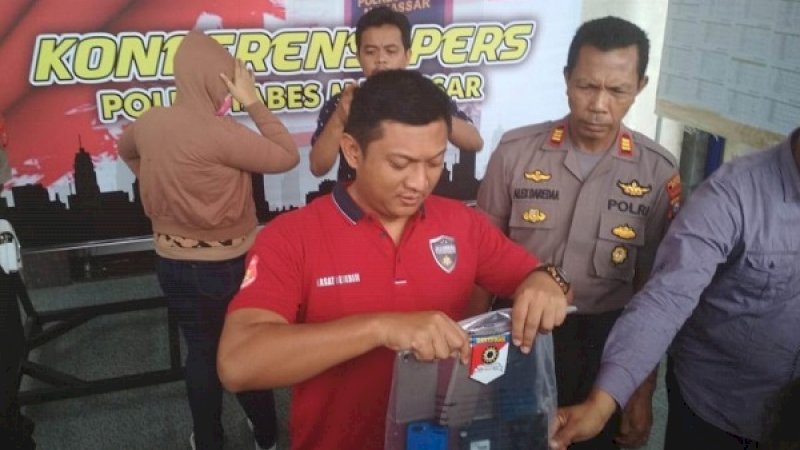 Kasatreskrim Polrestabes Makassar, AKBP Indratmoko (baju merah), memperlihatkan barang bukti prostitusi online muncikari A (jaket cokelat, membelakang) di Mapolrestabes Makassar, Sabtu (6/4/2019).