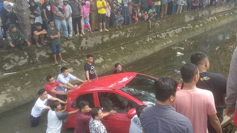  Sebuah mobil Honda Brio merah, dengan nomor polisi DW 1498 AJ, terjun bebas di sungai Jalan Sambaloge Baru, Kelurahan Masumpu, Selasa (30/4/2019).