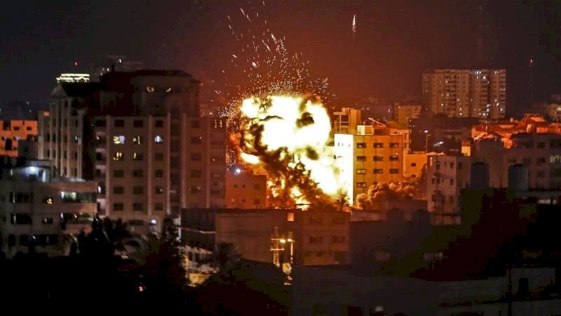 Sebuah ledakan terlihat di antara gedung-gedung selama serangan udara Israel di Kota Gaza pada 4 Mei [Mahmud Hams / AFP]
