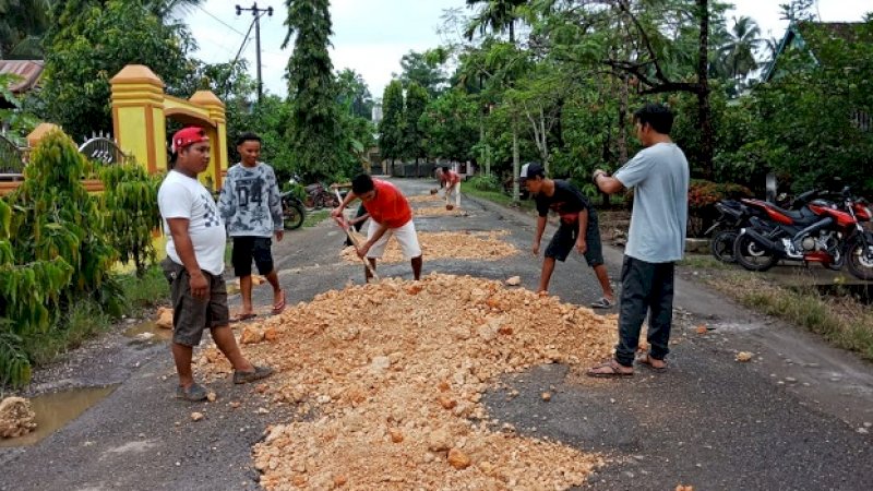 Kelompok pemuda Ujung Loe timbun jalanan rusak menggunakan batu kapur, Minggu (2/6/2019).