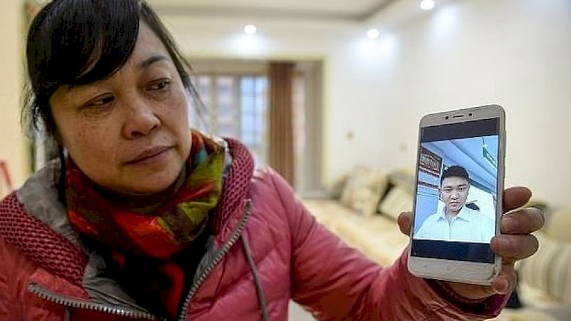 He Xiaoping menunjukkan foto putranya