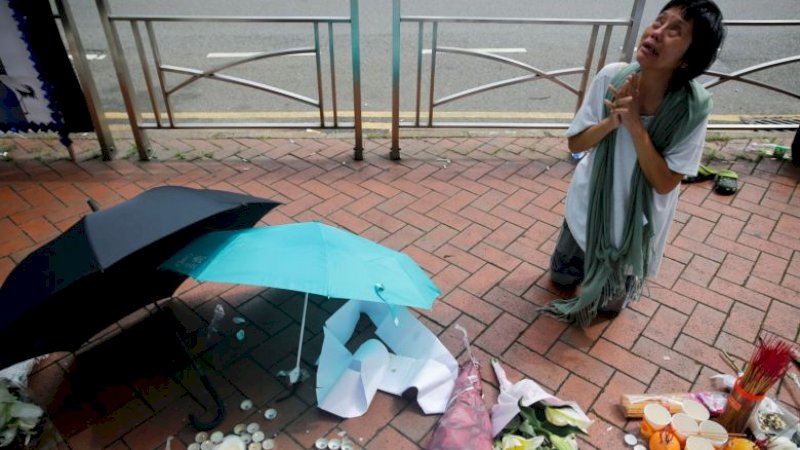 Seorang wanita berdiri di tempat di mana seorang pria jatuh dari Pacific Place (Reuters)