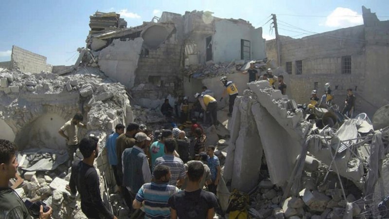 Pekerja pertahanan sipil Helm Putih Suriah mencari korban di bawah puing-puing bangunan yang hancur yang dihantam oleh serangan udara pemerintah Suriah, di kota utara Ariha, di Provinsi Idlib, Suriah, awal bulan ini. (via AP)