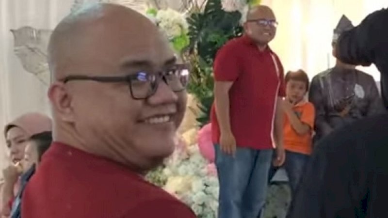 Seorang pria tertawa saat melihat orang yang mirip dengan dirinya di atas panggung pesta pernikahan di Malaysia.