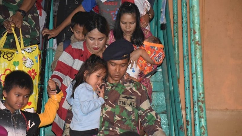 Seorang prajurit Lantamal VI, membantu menggendong anak-anak pengungsi dari Wamena yang tiba tadi malam di Pelabuhan Soekarno Hatta Makassar.