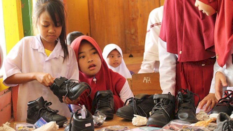 Para siswa mendapatkan bantuan sepatu.