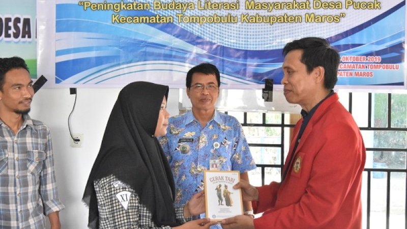 Wakil Dekan III Bidang Kemahasiswaan, Alumni dan Kemitraan FIB Unhas, Andi Akhmar (kanan), menyerahkan secara simbolis sebuah buku kepada seorang siswa.