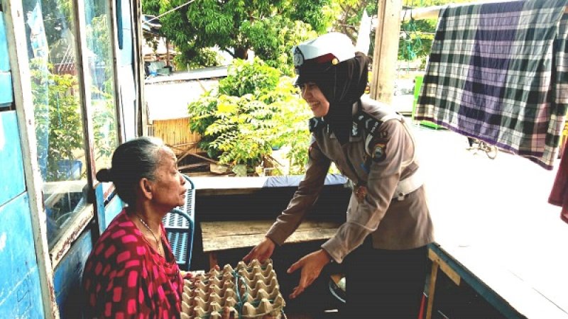 Seorang polwan memberikan sembako kepada seorang warga di Kota Sengkang.