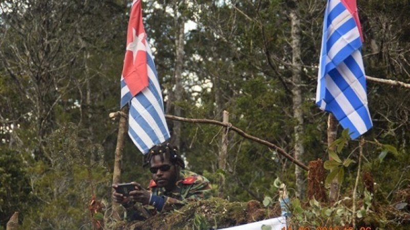 Salah seorang anggota OPM bersantai di depan dua bendera bintang kejora.