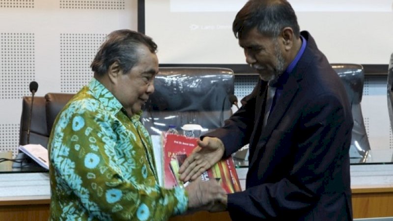 Prof Anwar Arifin menyerahkan buku kepada Dekan Fisip Unhas, Prof Armin Arsyad