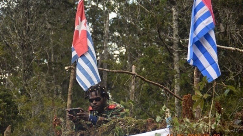 Salah seorang anggota OPM di antara bendera Bintang Kejora.