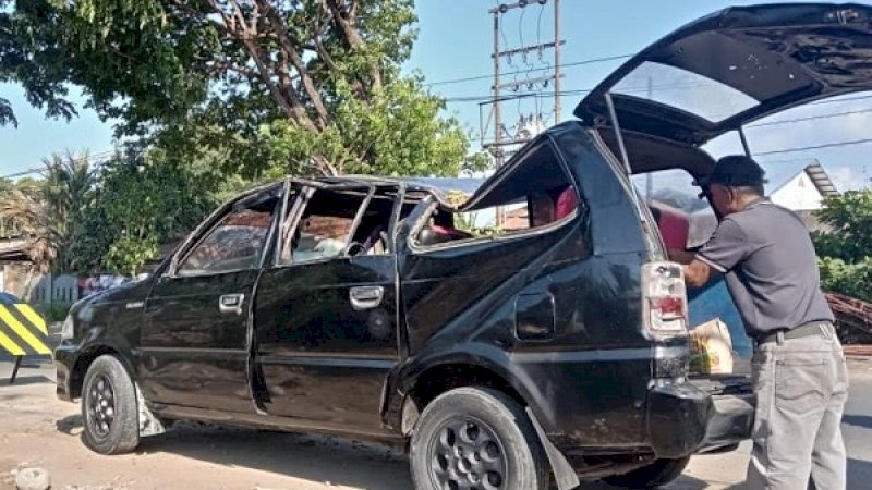 Mobil minibus hitam, penyok ditimpa pohon tumbang.