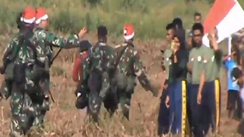 Penerjun TNI bertopi Sinterklas, membagikan bingkisan natal ke  warga.