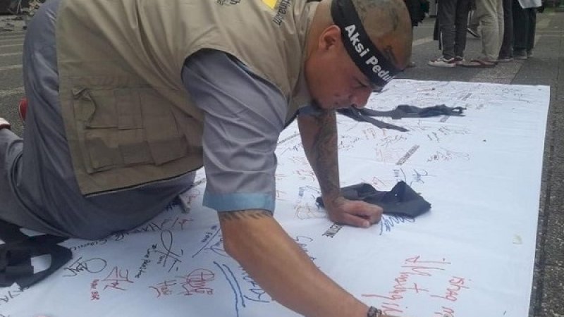 Ishaq Mustaqim membubuhkan tanda tangan dukung Palestina di atas spanduk putih.