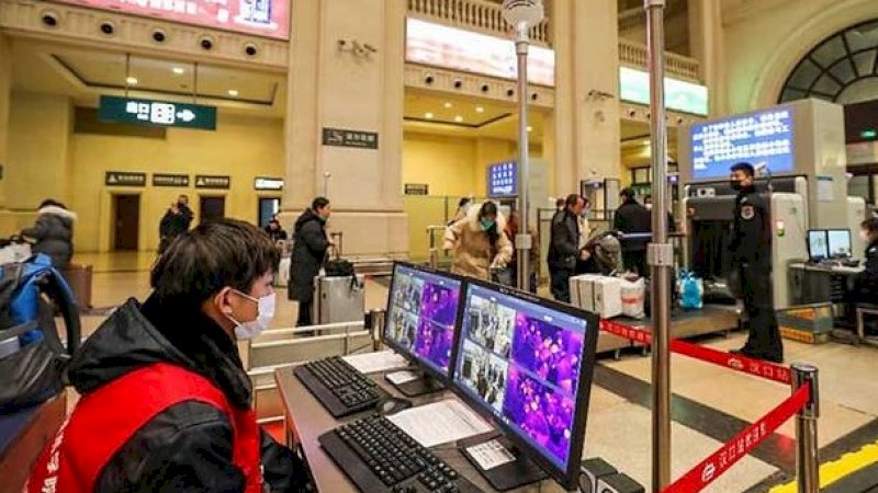 Seorang anggota staf memeriksa penumpang yang tiba di stasiun kereta api Hankou di Wuhan. (Foto AFP)
