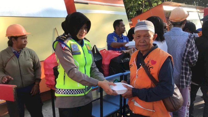 Anggota Ditlantas Polda Sulsel berbagi makanan kepada petugas di Lapangan Karebosi, Jumat (24/1/2020).