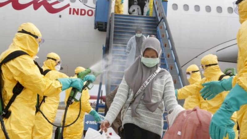 Petugas menyemprotkan cairan disinfektan kepada WNI yang baru saja tiba dari Wuhan, Minggu (2/2/2020).