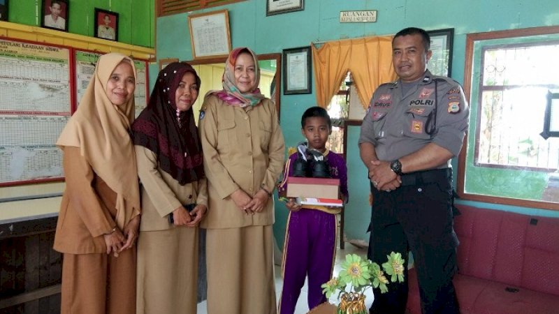 Bhabinkamtibmas Polsek Belawa, Aiptu Idrus menyumbang perlengkapan sekolah kepada seorang siswa SD 278 Belawa.