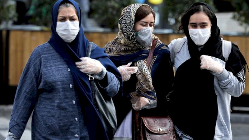 Orang-orang memakai masker di sebuah jalan di pusat kota Tehran. (AP)
