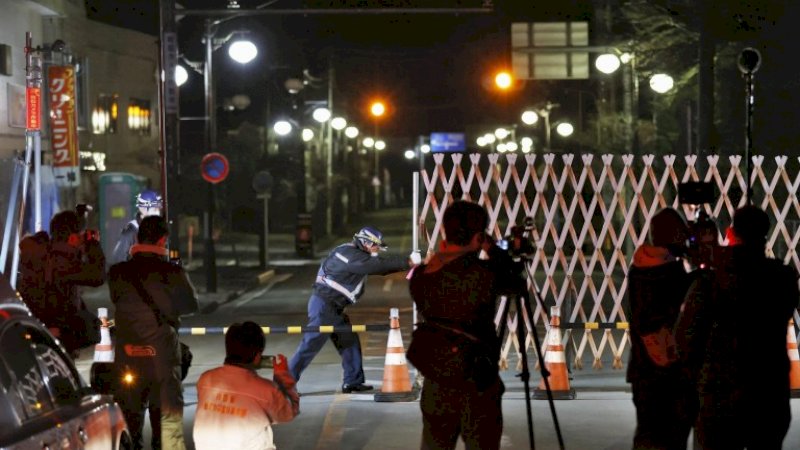 Seorang penjaga membuka gerbang ke kota Futaba (Foto: Kyodo via AP)