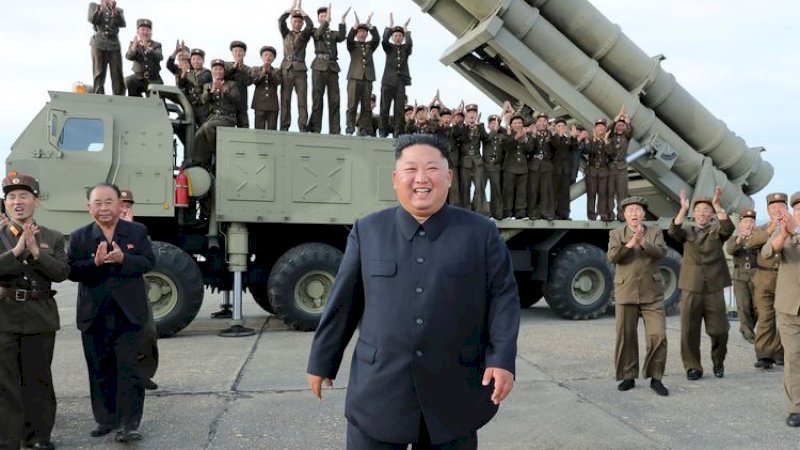 Kim Jong Un dengan latar belakang rudal yang siap diluncurkan. 