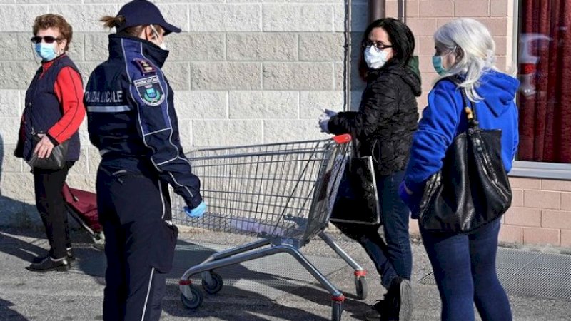 Seorang polisi memberi tahu perempuan tentang larangan bercampur saat berbelanja. (FOTO: AFP)