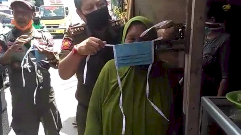 Satpol PP Sulsel memakaikan masker kepada warga.
