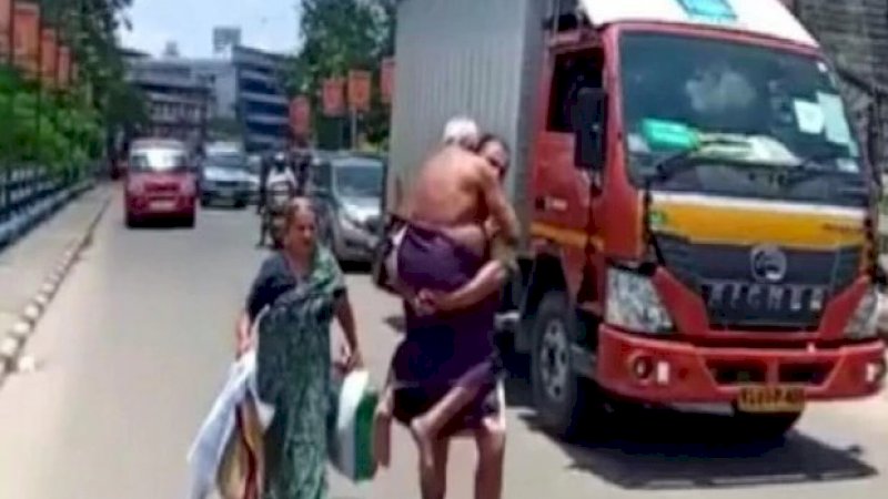 Seorang pria yang menggendong ayahnya yang baru keluar dari rumah sakit.