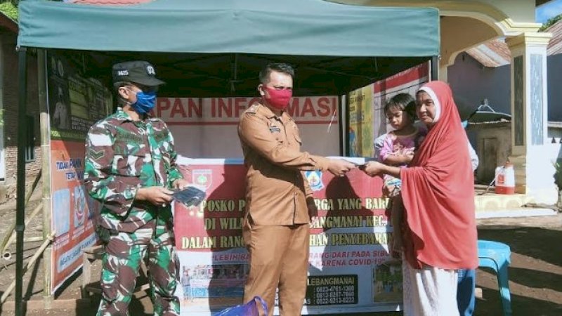 Kades Lebangmanai, Herman bersama Babinsa membagikan masker kepada warga.