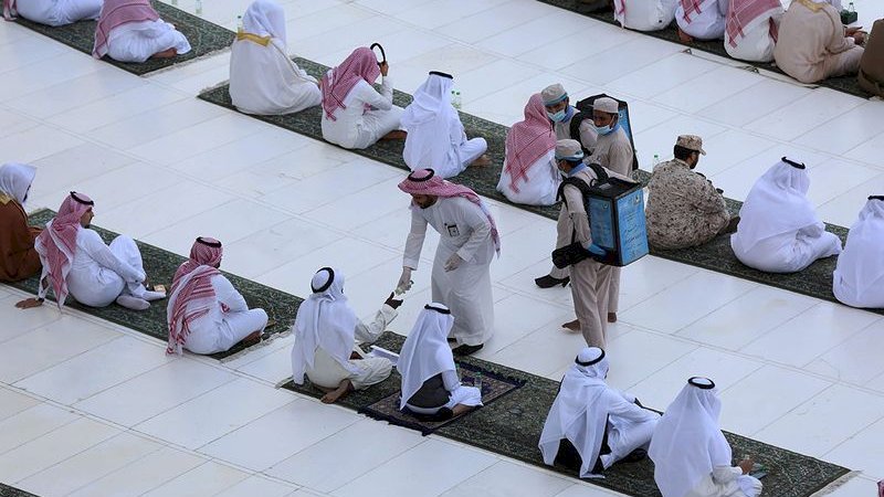 Tiga orang membagikan air zam-zam kepada jemaah salat Idulfitri di Masjidilharam, Minggu (24/5/2020).