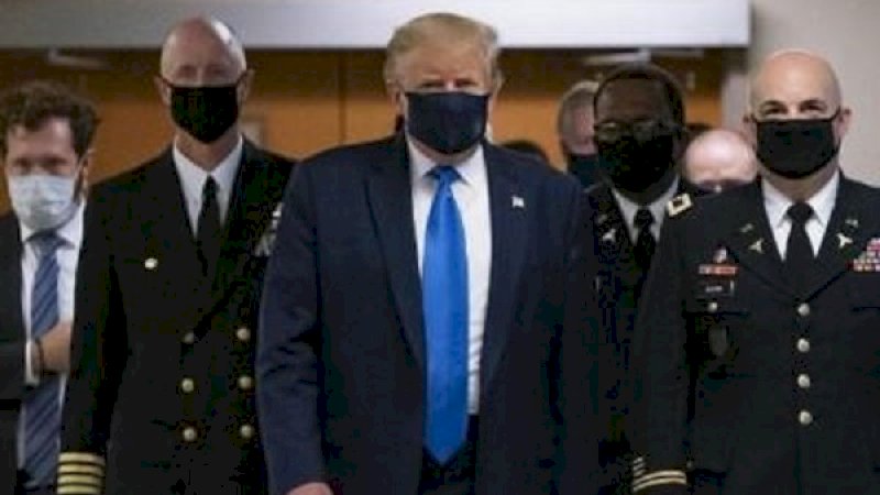 Donald Trump mengenakan masker warna hitam saat berjalan melalui koridor rumah sakit militer Walter Reed di luar Washington, Sabtu (11/7/2020) . (Foto: AFP)