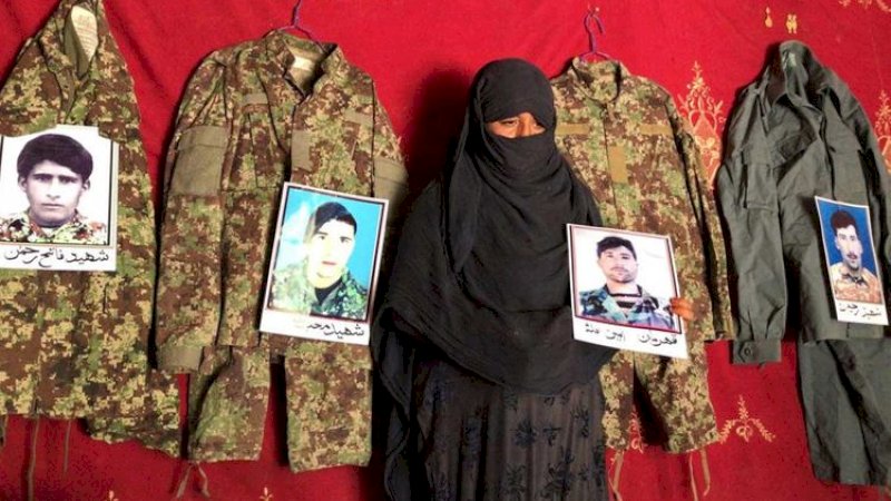 Taj Bibi memegang foto suaminya di samping seragam militer dan foto mantan suaminya yang terbunuh saat melawan Taliban, di rumahnya di Asad Abad, provinsi Kunar, Afghanistan, Minggu (20/9/2020). (FOTO: REUTERS)